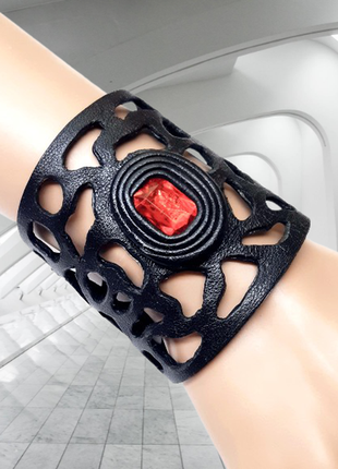 Широкий ажурный черный кожаный браслет с красным камнем.