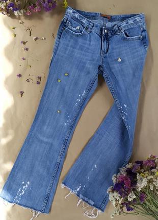 Клешные джинсы с фабричными потертостями, обрезанными штанинами