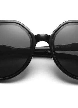 Солнцезащитные очки круглой формы в черной оправе.