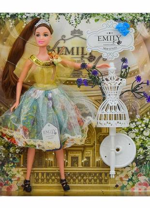 Лялька Emily Шатенка в сукні із золотистим верхом і манекеном
...